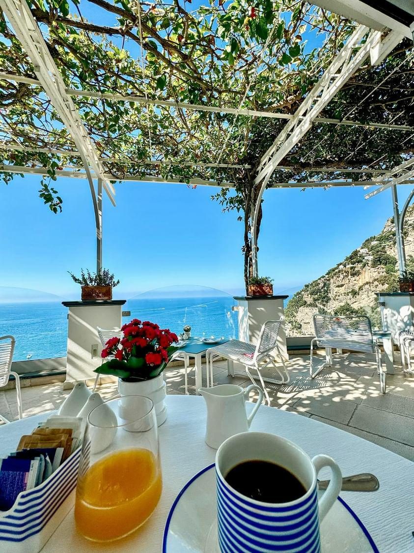 Breakfast on a vine-covered terrace over the coast, coffee and orange juice on the table