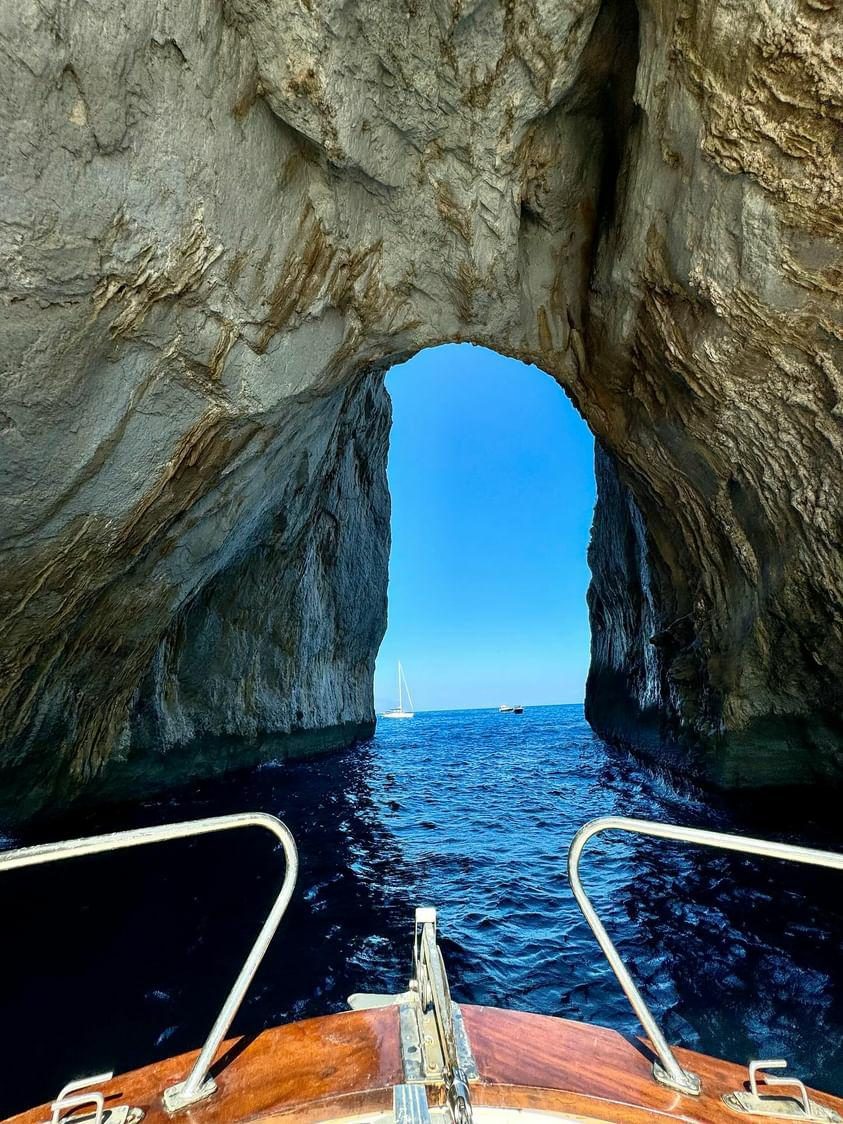 Looking through a sea-carved rock arch from the bow of a wooden boat