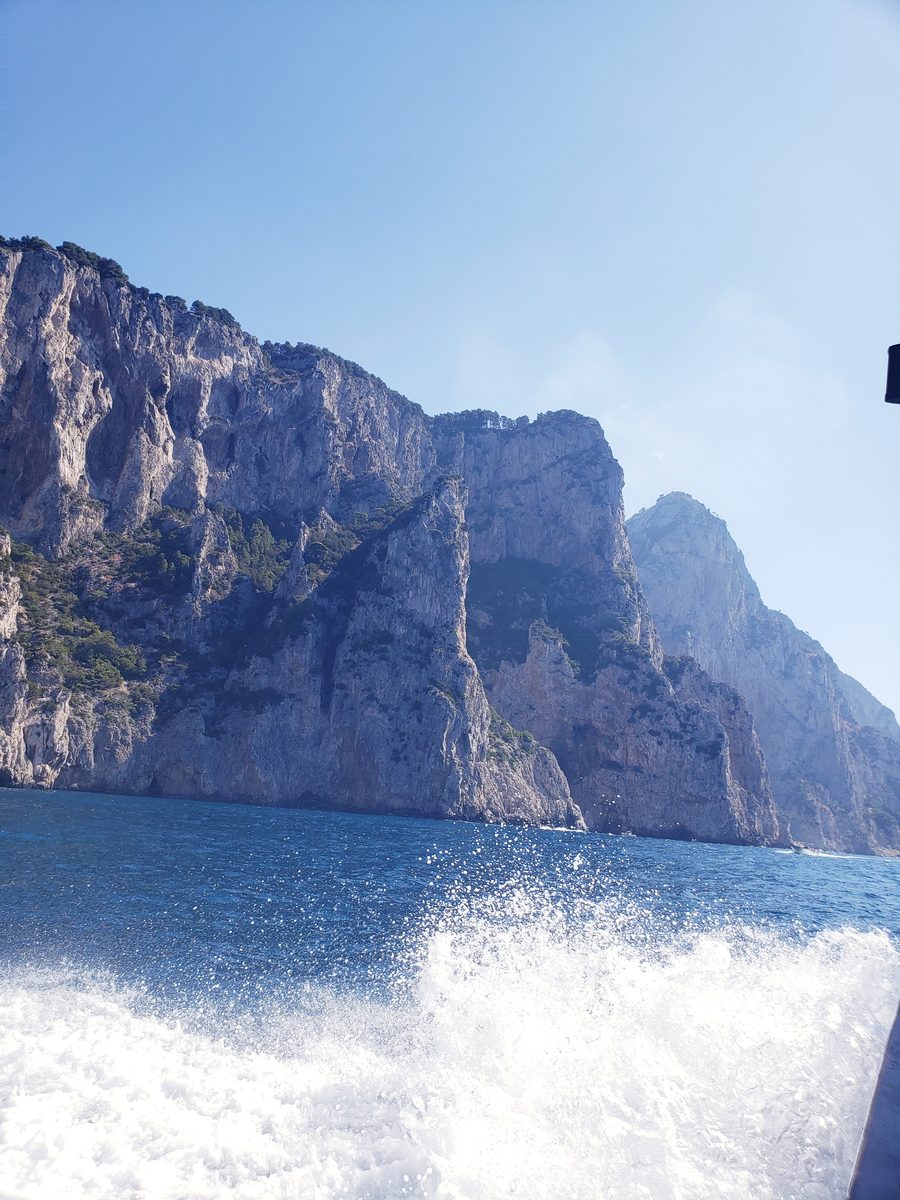 White spray off the bow, limestone cliffs rising from the water