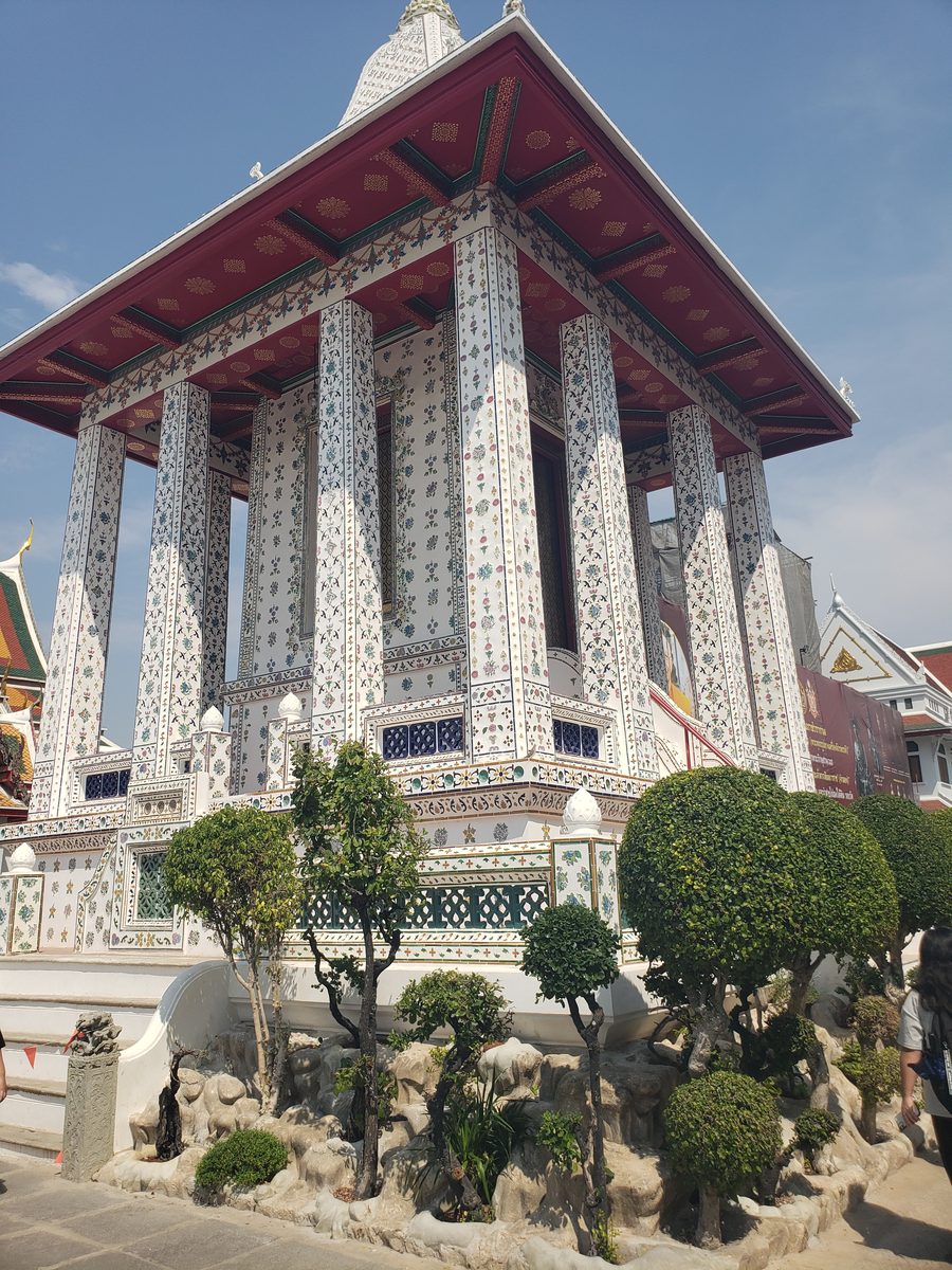A porcelain-inlaid pavilion and round topiary at Wat Arun