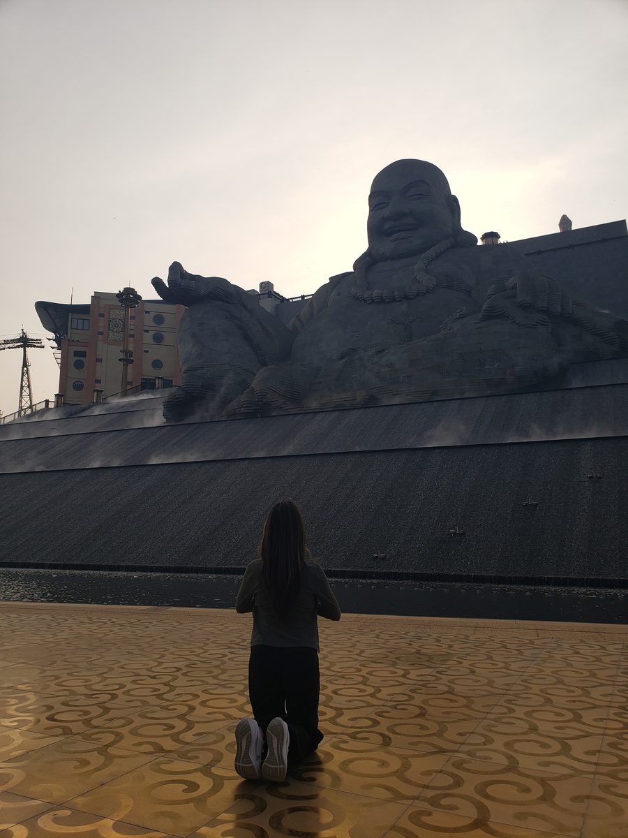 Linda kneeling before the Laughing Buddha at Ba Na Hills