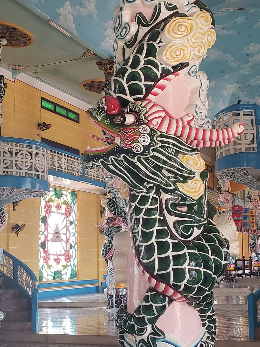 Green dragon coiled around a pink pillar inside a Cao Dai temple